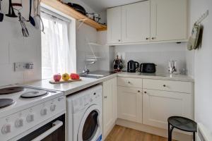 a kitchen with white cabinets and a dishwasher at Katrinas Apartment By Treetop Property in Cirencester