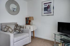 a living room with a couch and a television at Katrinas Apartment By Treetop Property in Cirencester