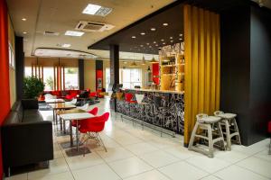 a restaurant with red chairs and tables and a bar at Ibis Bacabal in Bacabal