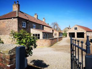 a fence in front of a brick house at Grange Farm Lodge in Ripon