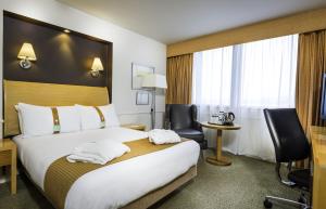 
a hotel room with two beds and a desk at Holiday Inn - Glasgow Airport, an IHG Hotel in Paisley
