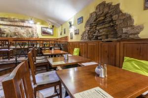 restauracja z drewnianymi stołami i krzesłami oraz kamiennym murem w obiekcie Hotel Klarinn Prague Castle w Pradze