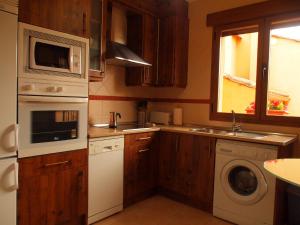 eine Küche mit Waschmaschine, Spüle und Mikrowelle in der Unterkunft LA CASA DE LAS AZAS in Casla