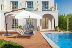 a house with a swimming pool and a white umbrella at Villa Luna in Vabriga