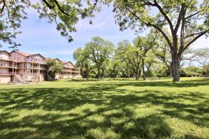 a large grass field with trees and buildings at Waterwheel Retreat in New Braunfels