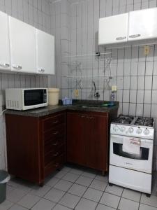 cocina con fogones blancos y microondas en Santoro Gali 310, en Florianópolis
