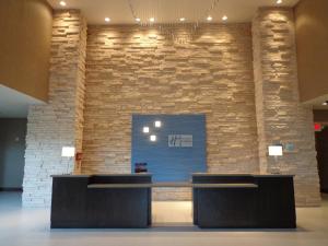 a lobby with two desks in front of a brick wall at Holiday Inn Express Frisco Legacy Park Area, an IHG Hotel in Frisco