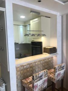 uma cozinha com armários brancos e um balcão com duas cadeiras em VIP Apartman KIKA Zlatibor em Zlatibor