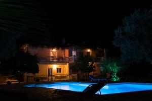 a swimming pool in front of a building at night at Doroufi Inn in Koilás