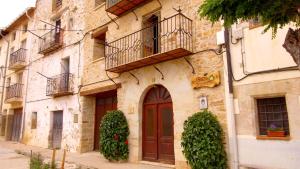 un antiguo edificio de piedra con puerta marrón y balcón en Apartamento Carrascales o Pinar Ciego, en Mosqueruela