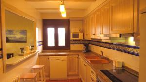cocina con armarios de madera, fregadero y ventana en Apartamento Carrascales o Pinar Ciego, en Mosqueruela