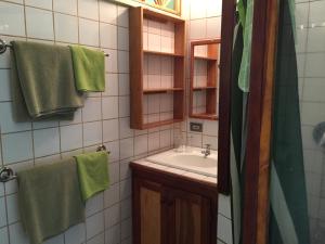 y baño con lavabo, espejo y toallas verdes. en Alibaba‘s Seabreeze, en Castara