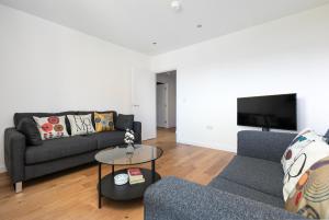 a living room with a couch and a tv at Skyvillion - Olympic View London Stratford Apartment in London