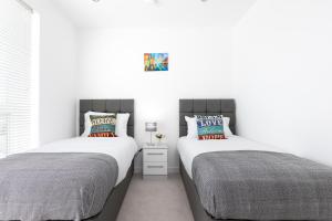two beds sitting next to each other in a bedroom at Skyvillion - Olympic View London Stratford Apartment in London