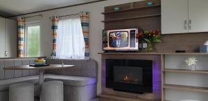 a living room with a fireplace and a tv at Waters Edge in Cirencester