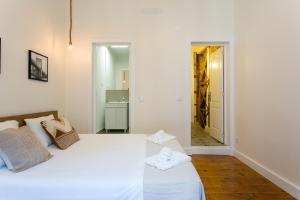 een witte slaapkamer met een wit bed en een spiegel bij Downtown Correeiros Apartments in Lissabon