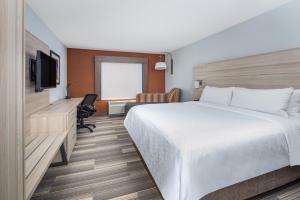 a hotel room with a bed and a desk and a television at Holiday Inn Express Ontario by IHG in Creekside