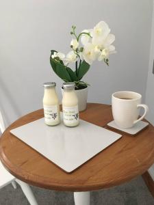 a table with two bottles and a cup and flowers at The Loft in Congleton