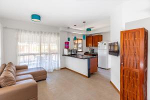 a living room with a couch and a kitchen at Cumbuco Dream Village Duplex with 3 bedrooms in Cumbuco