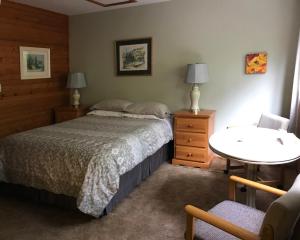 a bedroom with a bed and a table and a chair at Driftwood Village Resort in Sturdies Bay