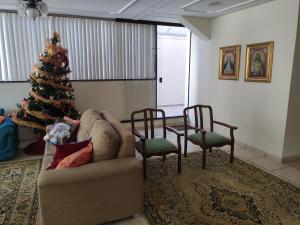 a christmas tree in a living room with a couch and chairs at Olga Kehdi Residence in Campo Grande