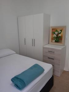Un dormitorio con una cama blanca con una toalla azul. en Apartamento Ilha dos Patos Ingleses na Beira do Mar, en Florianópolis