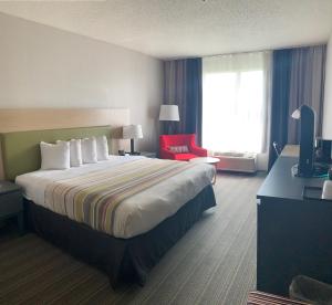 a hotel room with a large bed and a red chair at Sonesta Essential IAH Airport JFK Boulevard - Newly Renovated in Houston