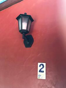 a street light on the side of a red wall at Regina Guest House in Praia do Rosa