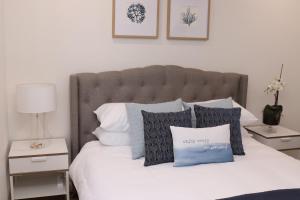 Una cama con almohadas azules y blancas. en Waterviews on Marine Pde 3/32, en The Entrance