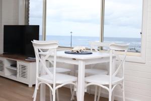 a white table with four chairs and a tv at Waterviews on Marine Pde 3/32 in The Entrance