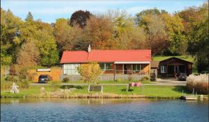 Liftlock Guest House في بيتربورو: منزل بسقف احمر بجانب بحيرة