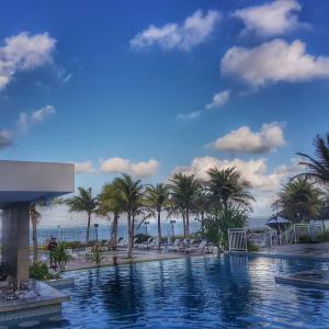 a swimming pool with palm trees and a beach at In Mare Bali Residencial Resort in Pium de Cima