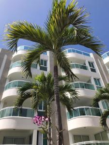 a palm tree in front of a building with pink flowers at In Mare Bali Residencial Resort in Pium de Cima