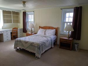 a bedroom with a bed and two tables and two windows at Spruce Lane Lodge and Cottages in Smoketown