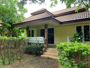 una pequeña casa amarilla con porche y escaleras en Khao Yai Cottage, en Mu Si