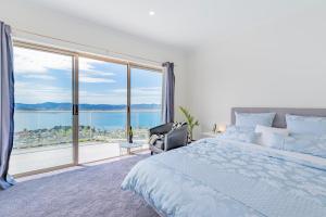 um quarto com uma cama e uma grande janela em Nature & Relax House, Panoramic sea view, Free parking 37 em Hobart