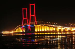 a lit up bridge over the water at night at Monoloog Hotel Surabaya in Surabaya