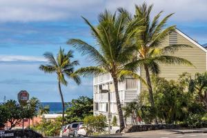 a building with palm trees in front of the ocean at Da Kona West 305 in Kailua-Kona