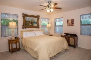 a bedroom with a bed with a ceiling fan and windows at Wine’D Up in Fredericksburg