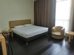 a bedroom with a bed and a chair and a window at Manja Hotel in Kota Kinabalu