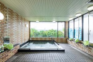 y baño con bañera de hidromasaje en una pared de ladrillo. en Kawaguchiko Station Inn en Fujikawaguchiko