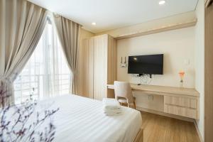 Cette chambre comprend un lit, un bureau et une télévision. dans l'établissement Luxy Park Hotel & Apartments - Notre Dame, à Hô-Chi-Minh-Ville