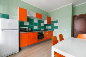 ノヴォシビルスクにあるApartments Freedom on Shamshinykhのキッチン(オレンジ色のキャビネット、テーブル、冷蔵庫付)