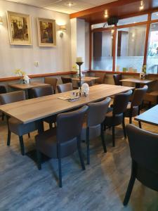 a restaurant with a large wooden table and chairs at City Hotel Meppel in Meppel