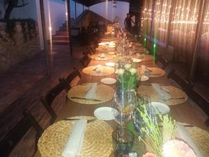 una larga mesa con platos y flores. en Masía Cal Simó empresas, retiros, familias,amigos,celebraciones,eventos,bodas, en Canyelles