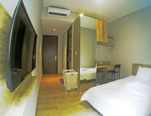 a bedroom with a bed and a desk and a tv at HM SOCIAL Karawaci in Tangerang