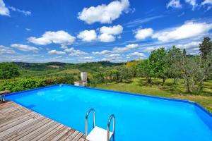 una piscina azul con terraza de madera con vistas en Maggiano by PosarelliVillas, en Certaldo