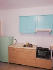 cocina con armarios azules, fregadero y microondas en Gouvia House Luxury Apartments en Gouvia