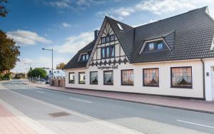 a white building with a black roof on a street at Hotel Grasberger Hof GmbH in Grasberg