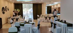 a banquet hall with white tables and chairs and people at Richmind Hotel in Vagharshapat